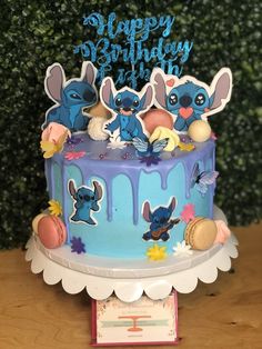 a birthday cake with blue frosting and cartoon characters on it, sitting on a table