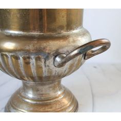 an antique brass urn with handles on a marble surface