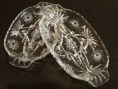 three clear glass dishes sitting on top of a black tableclothed surface with snowflakes in the middle