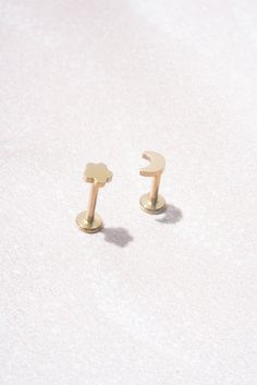 two gold - plated earrings are sitting on a white surface