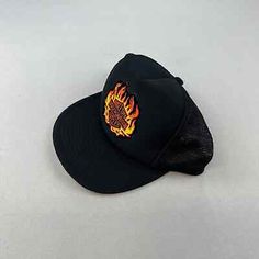 a black hat with flames embroidered on the front and side, sitting on a white surface