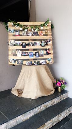 a wooden sign sitting on top of a set of steps next to a vase filled with flowers