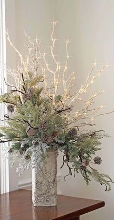 a vase filled with lots of greenery on top of a wooden table