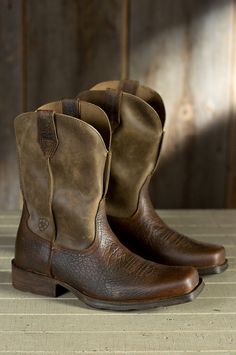 two brown cowboy boots sitting on top of a wooden table