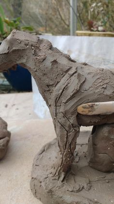 a clay horse statue sitting on top of a stone bench covered in mud and dirt