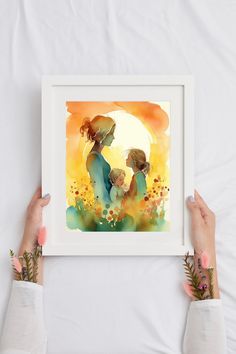 two hands holding up a watercolor painting with the sun setting behind them and flowers in front of them