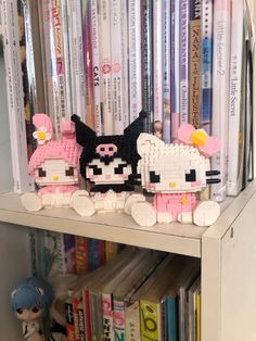 two hello kitty figurines sitting on top of a book shelf