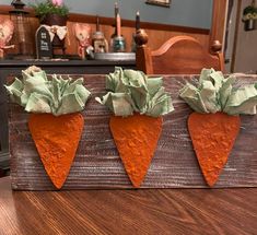 three carrots are sitting on top of a piece of wood that has been painted green and orange