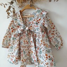 This charming baby girl dress is the perfect choice for any special occasion. Handmade with care, this boho-style dress features a delicate wildflower pattern, adding a touch of nature-inspired elegance. The large bow and ruffled details make it perfect for ceremonies, weddings, or even as a unique party outfit for your little one. This garment is made with 100% high quality fabric (cotton). Each garment is designed, printed, cut, sewn, photographed and packaged in our own studio. Order today an Cute White Dress With Ditsy Floral Print, White Bohemian Floral Dress With Ruffles, Multicolor Floral Print Cottagecore Dress, Cottagecore Multicolor Floral Print Dress, Cute Cotton Ditsy Floral Dress, Cute Cotton Ditsy Floral Print Dress, Bohemian Cotton Dress With Ditsy Floral Print, Cottagecore White Floral Dress, Whimsical Long Sleeve Summer Dresses