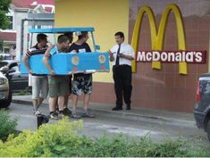 some people are standing in front of a mcdonald's and one is holding a cardboard box