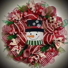 a christmas wreath with a snowman wearing a top hat and candy canes on it