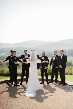 a bride and groom standing with their arms out in front of the bridal party