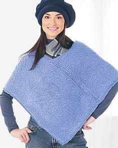 a woman standing with her hands on her hips wearing a blue poncho and hat