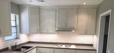 an empty kitchen with white cabinets and gray counter tops is seen in this image from the doorway