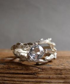 a silver ring with a crystal stone in the center on top of a wooden surface