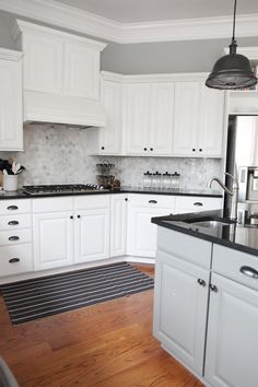 a kitchen with white cabinets and wood floors is shown in this color scheme for the walls