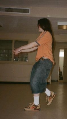 a woman in an orange shirt is playing with a frisbee on the floor