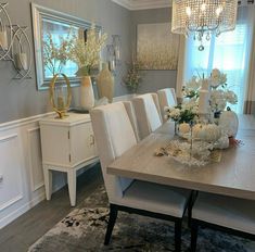 a dining room table with white chairs and chandelier