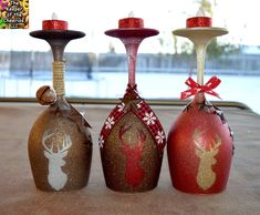 three wine glasses decorated with deer heads and red glitters are sitting on a table in front of a window