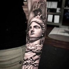 a woman's arm with a tattoo on it and a statue in the background