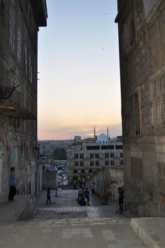 people are walking up and down the stairs in an alley way with buildings on both sides