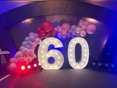 the number sixty sign is lit up with balloons