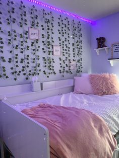 there is a bed with pink sheets and pillows in the room that has ivys on the wall