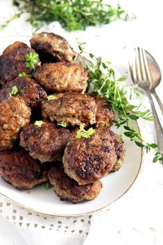 some meatballs on a white plate with green garnish and a fork next to it