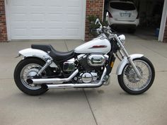 a white motorcycle parked in front of a garage