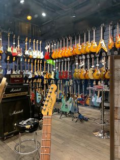 guitars and amps are on display in a music store with other instruments hanging from the ceiling