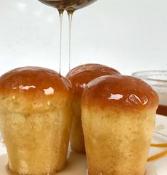 two muffins on a plate with syrup being drizzled over them