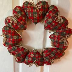 a red and green plaid heart shaped wreath hanging on a white door with burlocks