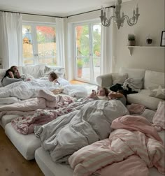 three children are sleeping on the couches in their living room with pink and white comforters