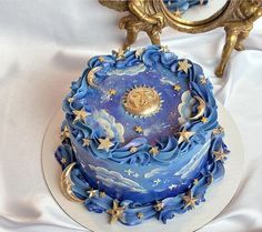 a blue and white cake with gold stars on it sitting on a platter next to a mirror