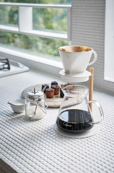 a coffee maker sitting on top of a counter next to a cup and saucer