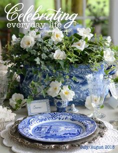 a blue and white plate sitting on top of a table next to a vase filled with flowers