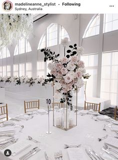 the table is set with silverware and flowers in tall vases on each side