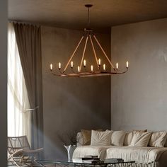 a living room filled with furniture and a chandelier hanging from the ceiling next to a window