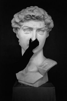 a black and white photo of a statue with a glove on it's face