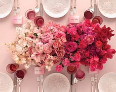 a table with plates, silverware and pink flowers on the wall above it is set for a formal dinner