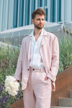 a man in a pink suit and white shirt is standing on some steps with his hands in his pockets