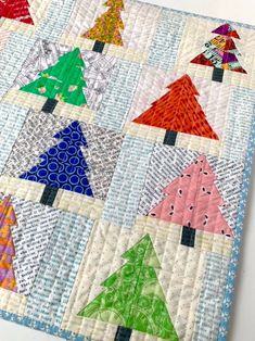 a quilted table topper with many different colored christmas trees on the front and back