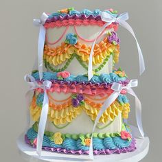 a multi - tiered cake decorated with flowers and ribbons