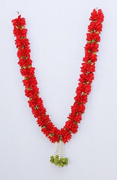 a red necklace with green beads and flowers on it's end, hanging from a white wall