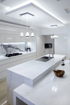 a modern kitchen with marble counter tops and white cabinets, along with an island in the middle