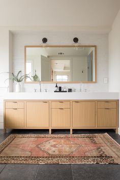 a bathroom with a rug, sink and mirror