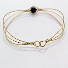 A sweet design of three strands of 14kt gold filled wire featuring a single 6mm genuine garnet bead flanked by two small 14kt gold filled beads. The garnet bead is a very deep dark red, almost black (unless you hold it up to the light or next to something that's actually black!) This stylish, well-fitting bangle will go with most everything in your closet, and is sure to get noticed every time you wear it. So delicate and feminine! The sturdy built-in hook and eye clasp is easy to get on and off Simple Pearl, Pearl Bangle, Wire Bangles, Bead Bangles, January Birthstone, Gemstone Beaded Bracelets, Gold Wire, Red Garnet, 14kt Gold