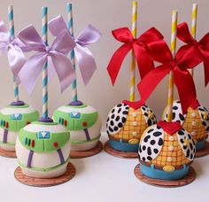 there are some cake pops decorated like cartoon characters and with bows on them, sitting next to each other