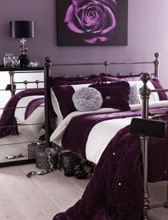 a bedroom with purple and white bedding in the corner, mirror nightstands on either side