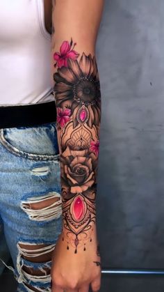 a woman's arm with flowers and hearts tattooed on her left arm, in front of a gray wall